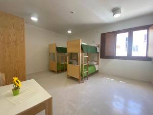 a room with two bunk beds and a table at Posada Eco-Ostello di Buggerru in Buggerru +2 photos