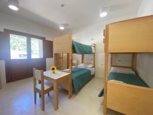 a bedroom with bunk beds and a table and a desk at Posada Eco-Ostello di Buggerru in Buggerru