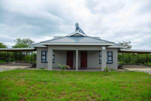 a small white building with a roof on a grass field at Tree Tops Game Resort in Magomba