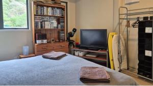 a bedroom with a bed and a tv and a book shelf at Whareupoko in Waimarama