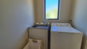 a small bathroom with a sink and a washing machine at Whareupoko in Waimarama +28 photos
