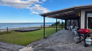 a house with a deck with a view of the ocean at Whareupoko in Waimarama