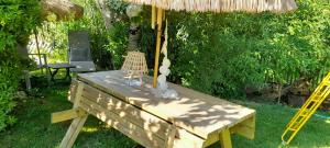 a wooden table with an umbrella in a yard at Au Bois Dormant in Monterblanc +9 photos