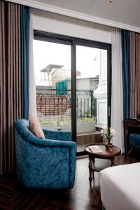 a living room with a blue chair and a window at Eli Suites in Hanoi