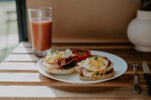 a plate with two breakfast sandwiches on a table with a drink at Nomad Nation by Tiny Away in Mount Perry