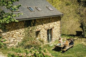 a group of people sitting on a bench in front of a stone building at La montana in Seix