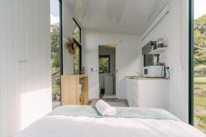 a bedroom with a white bed and a kitchen at Rainforest Sunsets by Tiny Away in Kuranda