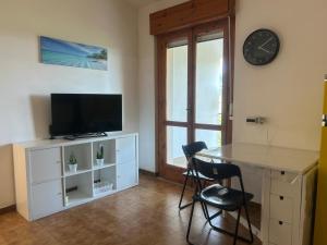 a living room with a table and a tv and a clock at Casa COMER GRISOLIA in Cirella