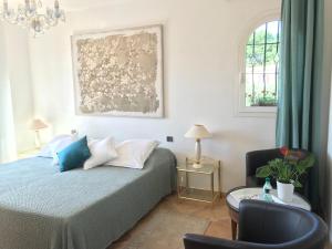 a bedroom with a bed and a chair and a window at Bastide Rose de Mai in Le Rouret