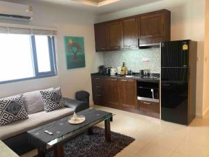 a living room with a couch and a kitchen at Apartment Eliza Samui in Garden Resort with Shared Pool in Plai Laem