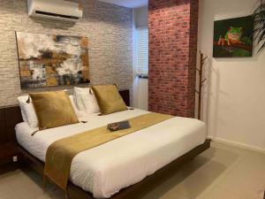a bedroom with a large bed with a brick wall at Apartment Eliza Samui in Garden Resort with Shared Pool in Plai Laem +14 photos