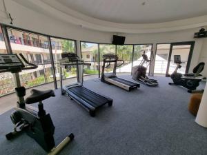 a gym with several tread machines in a room with windows at Apartment Eliza Samui in Garden Resort with Shared Pool in Plai Laem