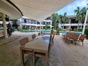 a patio with a table and chairs next to a pool at Apartment Eliza Samui in Garden Resort with Shared Pool in Plai Laem