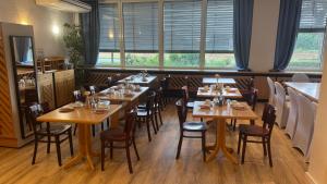a restaurant with wooden tables and chairs and windows at Hotel Störtebeker in Biendorf