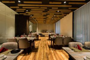 a restaurant with tables and chairs in a room with wooden floors at OPO Horizon Aerocity ,Delhi Airport in Jāmb