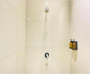 a shower with a shower head on a white wall at Alhambra Hotel Banda Aceh in Banda Aceh