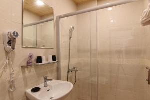 un bagno bianco con doccia e lavandino di Zi Jìng Fang Inn a Città Vecchia di Hengchun
