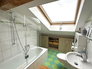 a bathroom with a sink and a bath tub and a window at Ferienwohnung Scheibenwand-Loft in Aschau im Chiemgau +13 photos