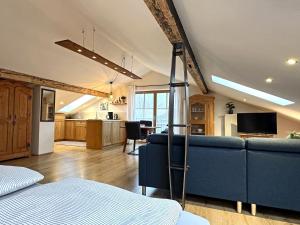 a living room with a blue couch and a kitchen at Ferienwohnung Scheibenwand-Loft in Aschau im Chiemgau
