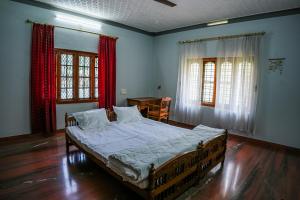a bedroom with a bed and a table and windows at Athira Homestay in Kollengode