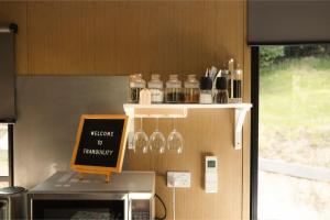a counter with glasses and a sign on a microwave at Tranquility Tiny House by Tiny Away in Owaka