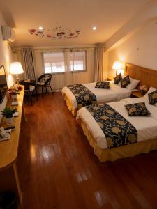 a hotel room with three beds and a table at 八零年代客栈 in Hanqiyu