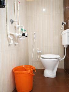 a bathroom with a toilet and an orange bucket at Hotel Mayur Lodge in Bijāpur