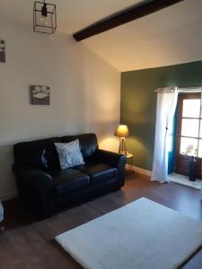 a living room with a black couch and a window at The Old Forge in La Ressière