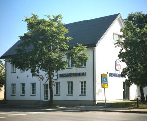 a white building with a tree in front of it at Loft Apartment Self Check-in in Mažeikiai