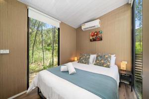 a bedroom with a large bed with a large window at Wildlife Haven by Tiny Away in Agnes Water