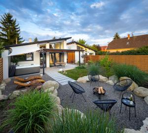 a backyard with chairs and tables and a house at White Lotus Mini Loft House in Mezőkövesd
