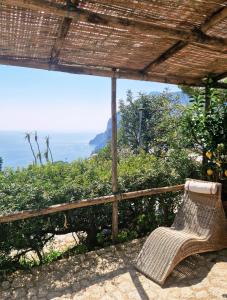 Ein Rattanstuhl steht auf einer Veranda und blickt aufs Meer hinaus in der Unterkunft Casa Laboccetta in Capri