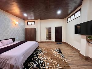 a bedroom with a bed and a flat screen tv at Valley Roots Homestay in Ziro