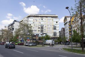 a large white building on a city street with cars at Apartment Orchid 021 in Novi Sad
