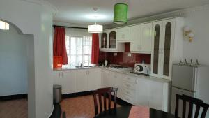 a kitchen with white cabinets and a table and a refrigerator at rossylyn lonetree two bed bedroom in Nairobi