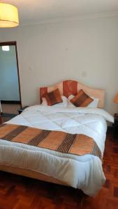 a bedroom with a large bed with white sheets at rossylyn lonetree two bed bedroom in Nairobi
