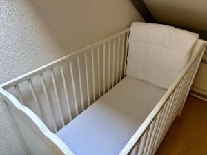 a crib with a white seat in a room at House & garden l'Hippodrome in Bredene