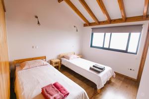 two beds in a room with a window at Casa da Petra in Urzelina