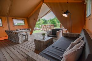 a wooden deck with a couch and a table at Glamping Drouwenerzand in Drouwen