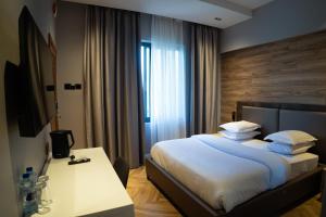 a bedroom with a bed with a desk and a window at Silverado Boutique Hotel in Tanga