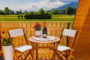 a table with a bottle of wine and two chairs at Komac Apartma & Glamping BLED in Bled