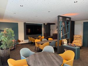a waiting room with tables and chairs and a flat screen tv at Hochwald Lodge in Morbach