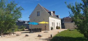 a building with chairs and umbrellas in front of it at Fermette Tourangelle in Bréhémont