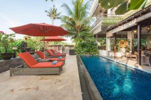 a pool with chairs and umbrellas next to a house at The Magic Villa in Lebih