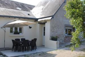 a table with chairs and an umbrella on a patio at Gîtes La Grenouillère in Veuzain-sur-Loire
