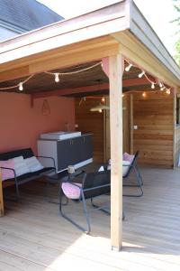 a pavilion with a grill and chairs on a deck at Gîtes La Grenouillère in Veuzain-sur-Loire