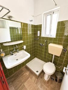 a green tiled bathroom with a toilet and a sink at Asterias in Koronisía