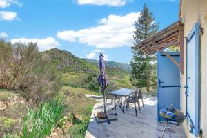 a table and chairs on a deck with a grill at Location Gîte Les Iris in La Robine