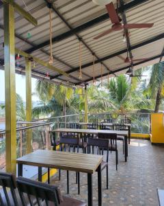 a restaurant with wooden tables and chairs and palm trees at Calangute house inn in Calangute