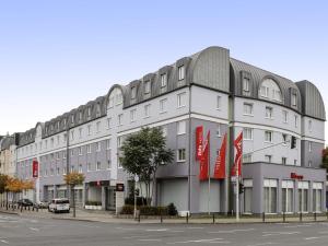 a large white building with red flags in front of it at ibis Mainz City in Mainz